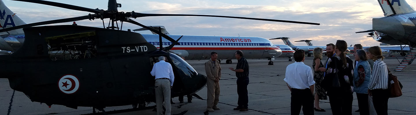 people standing around helicopters and airplanes